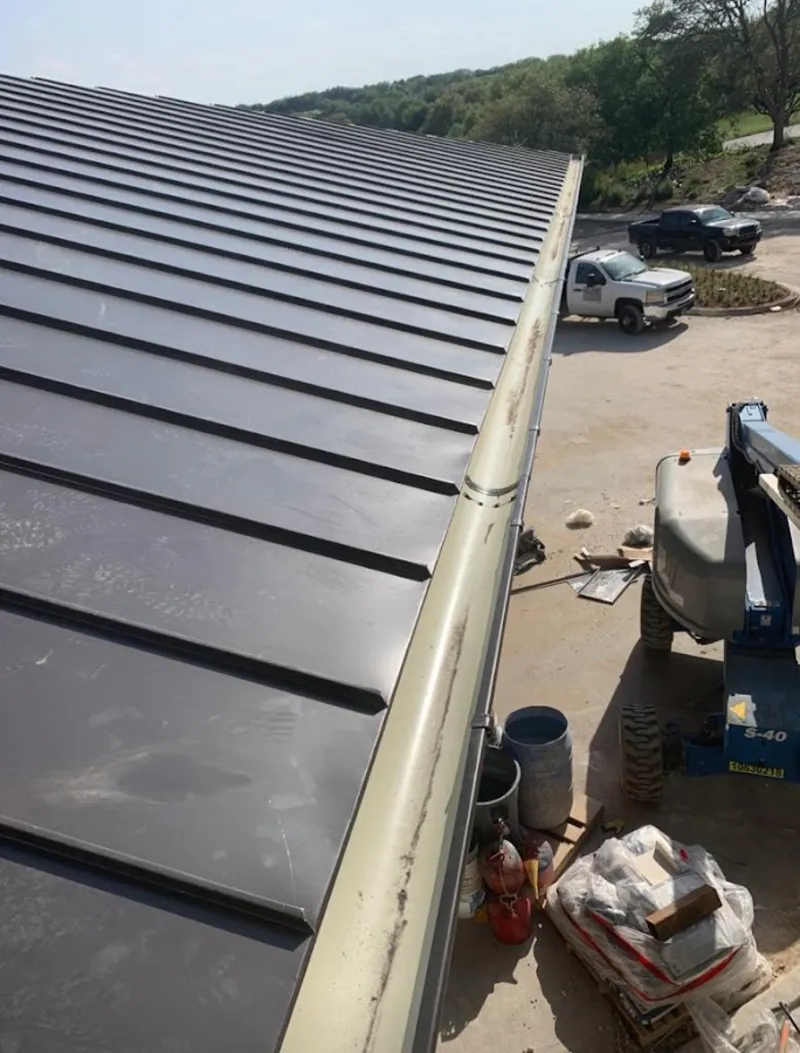 Standing seam panel and gutter detail on a metal roofing jobsite in Howard